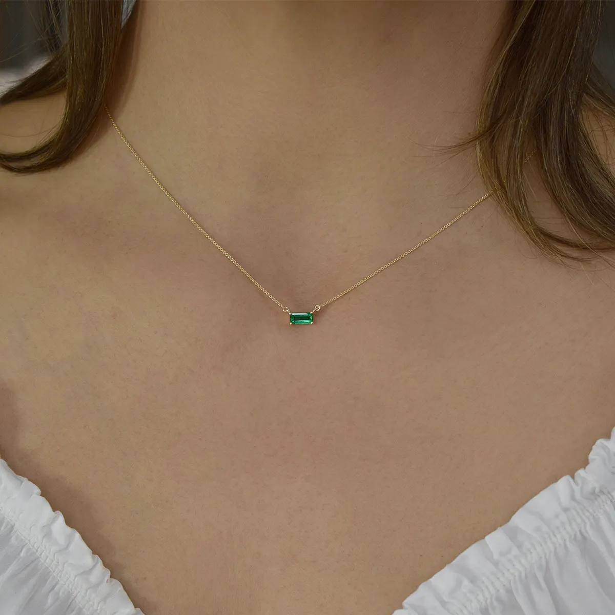 east_west_emerald_cut_emerald_necklace_yellow_gold.webp